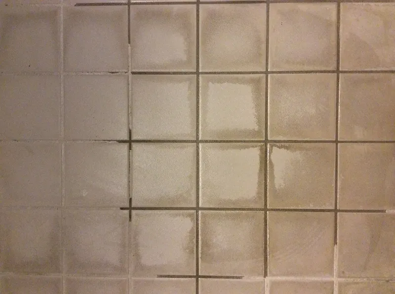 Why do stains and mold appear on ceramic and porcelain tiles?